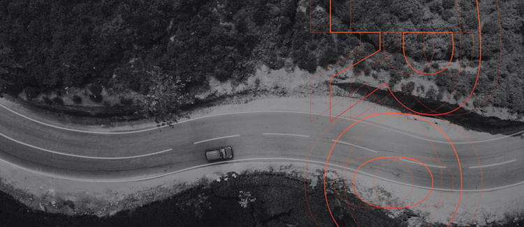 Seen from above, a car drives on a curving road.