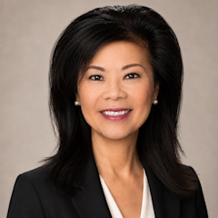 Colleen Pham with long black hair smiles in a professional headshot, wearing a black blazer and white blouse, with pearl earrings.