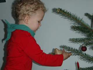 Ein kleiner Junge hängt Weihnachtsschmuck an den Baum