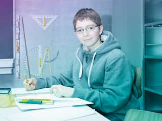 Nico macht Schulaufgaben an seinem Schreibtisch