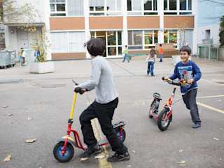 Kinder spielen mit Trottinet auf dem Pausenplatz