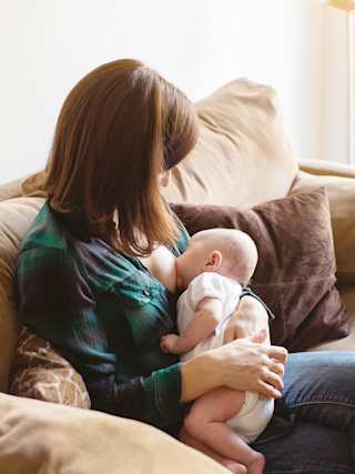 Mutter stillt Baby auf dem Sofa