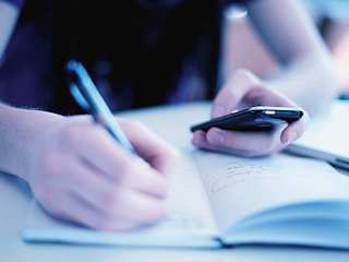 Schulkind macht Aufgaben und schaut auf dem Handy