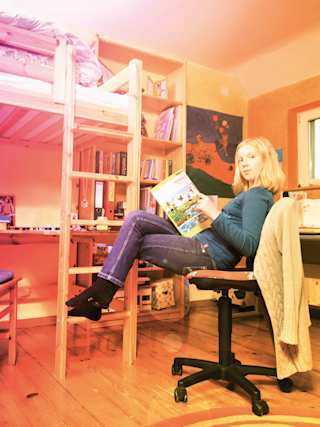 Hanna sitzt auf einen Bürostuhl in ihr Zimmer.
