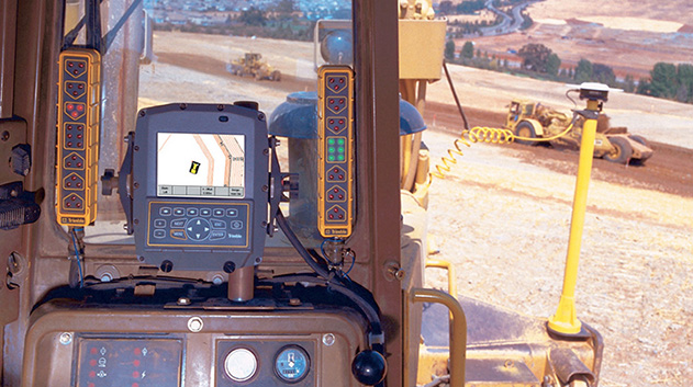 A view from the interior of a construction vehicle's cab, looking out at a dirt construction site.