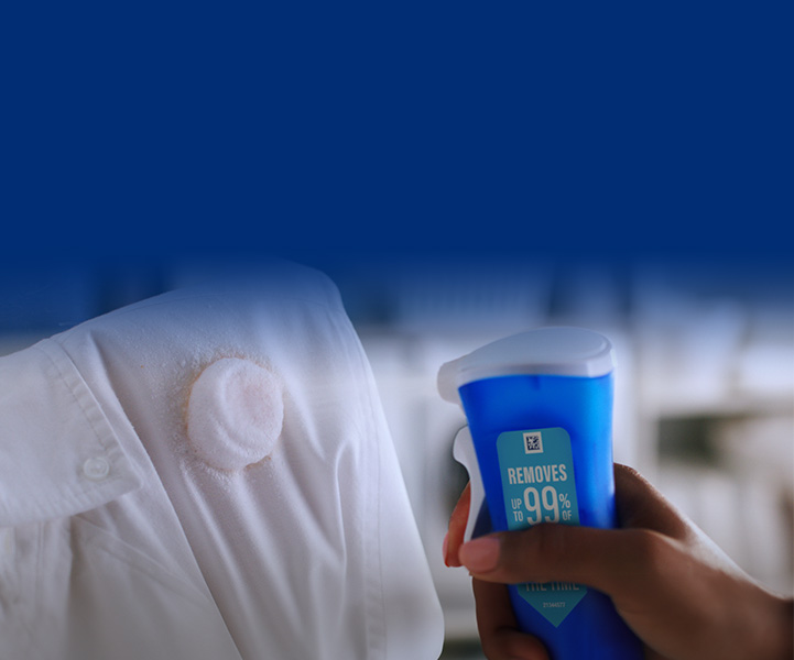 A hand holds Dawn Powerwash and squirts a stain on a white shirt