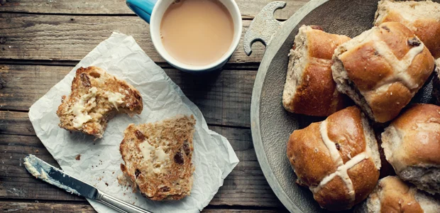 a stack of hot cross buns with butter and a cup of tea a stack of hot cross buns with butter and a cup of tea
