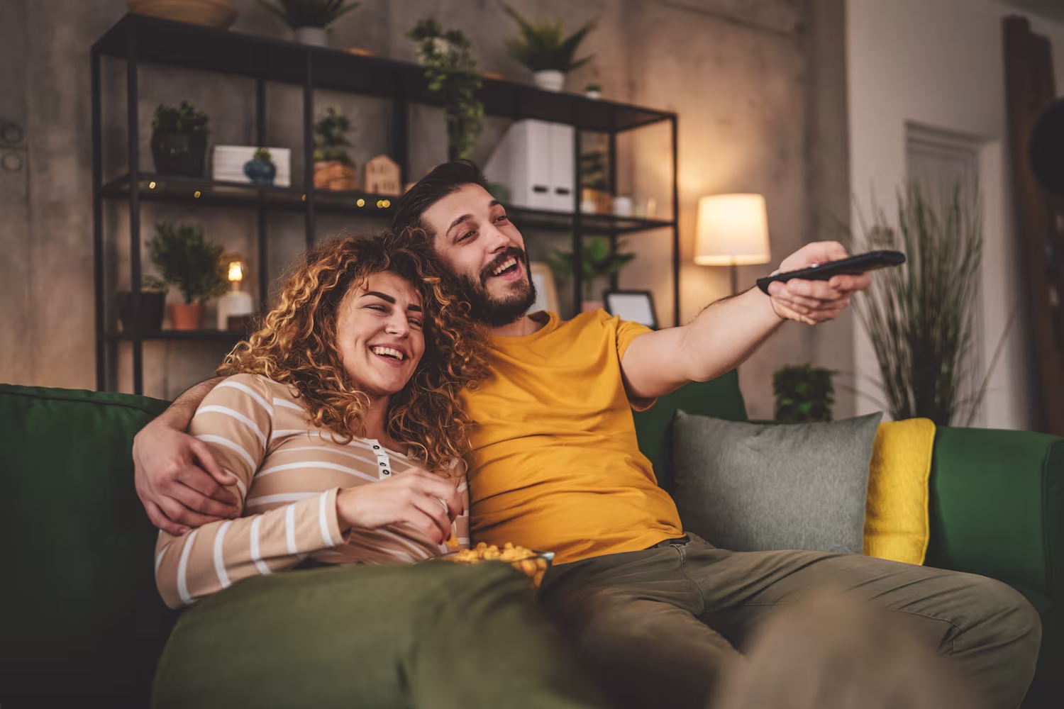Serie TV romantiche da vedere: coppia sul divano con telecomando
