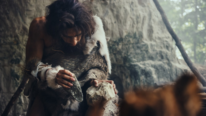 stone age man making a tool - shutterstock