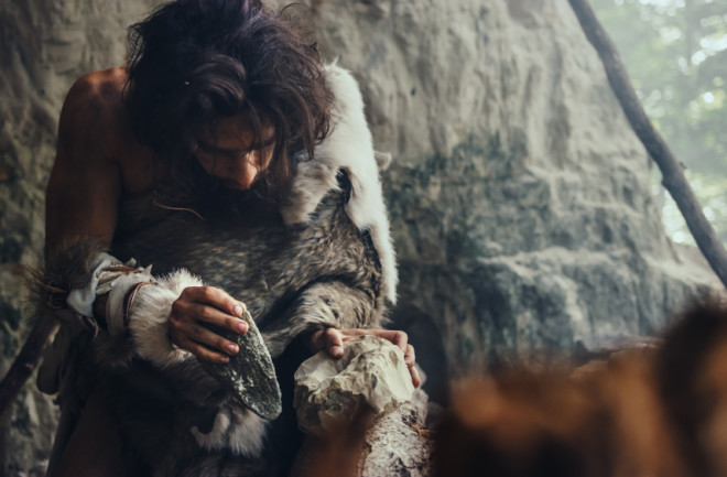 stone age man making a tool - shutterstock