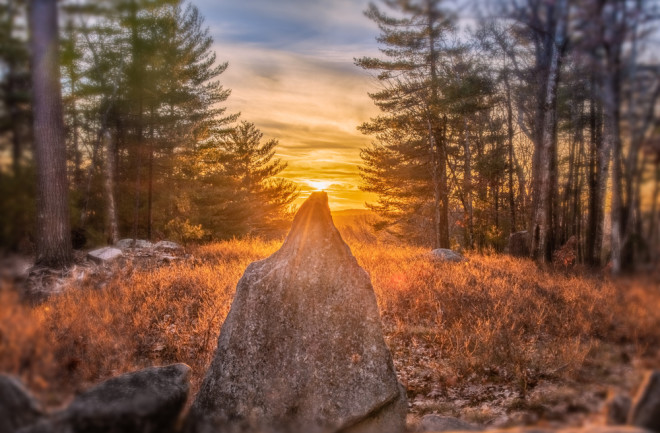 Sun setting on the winter solstice stone at America's Stonehenge - shutterstock