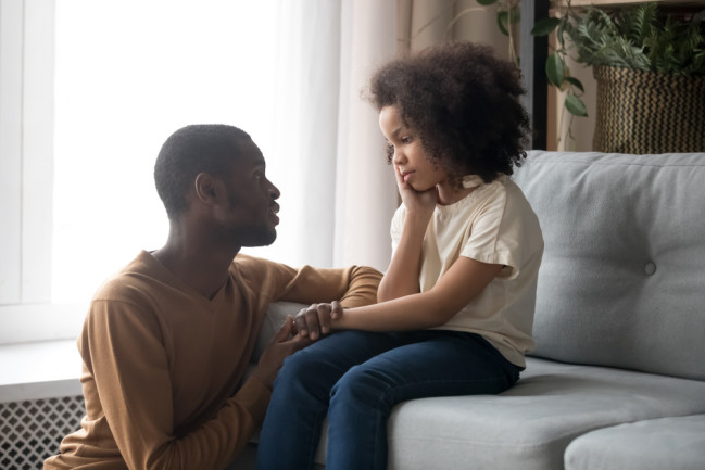 Father comforting child in living room - shutterstock