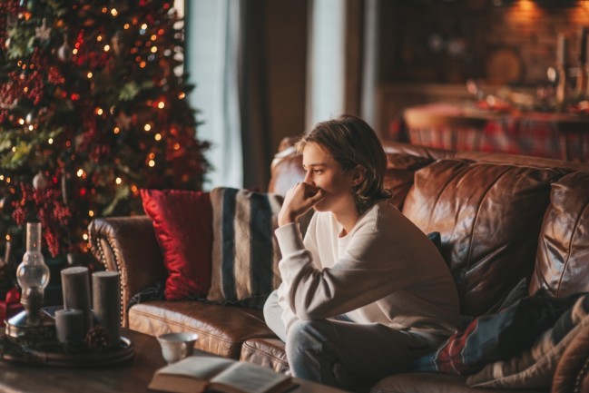 teenager alone on couch by christmas tree solemn