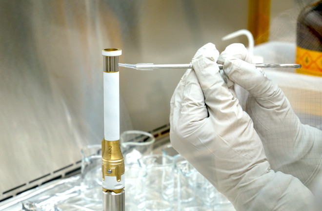 A technician examines one of Perseverance's sample tubes at the Jet Propulsion Laboratory. When the tube returns to Earth, it will contain Mars rocks and, just maybe, hints of alilen life. (Credit: NASA-JPL/Caltech)