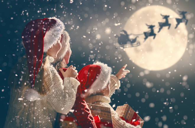 Santa Claus soars through the sky on a sleigh pulled by reindeer.