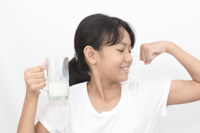 Portrait of Asian lovely girl drinking milk from glass on a white background