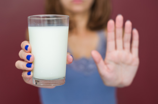 Woman hand in deny, saying no to drinking dairy milk.  Lactose intolerance and dairy problem concept