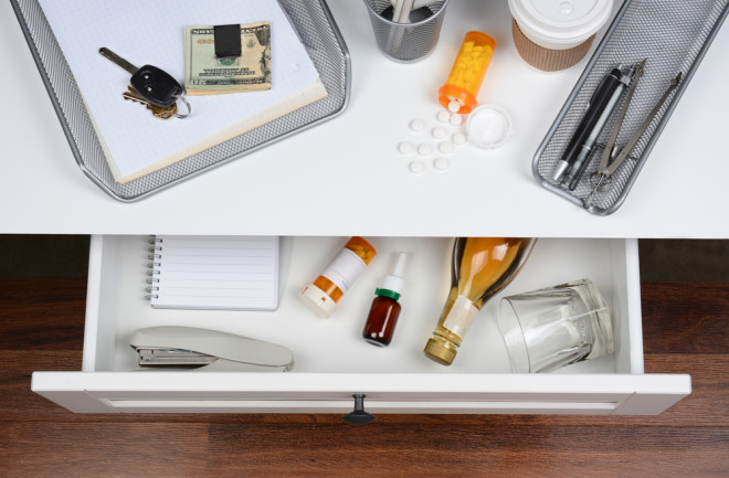 Desktop scene showing pills, coffee, and alcohol in a drawer - Shutterstock