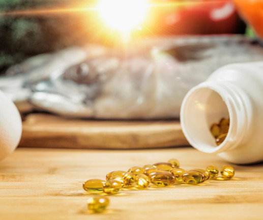 vitamin D Supplement Bottle with Gel Capsules On a Wooden Table. Natural Food Sources of Vitamin D In Background.