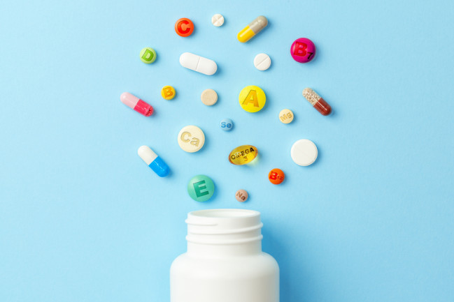 white pill bottle with multiple colorful multivitamins