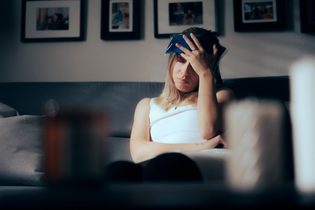 Sick Woman Using an Ice Bag o Alleviate Migraine - stock photo Unhappy person having a headache after physical injury at home