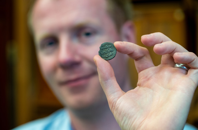 Cambridge University historian Rory Naismith holding Anglo Saxon coin