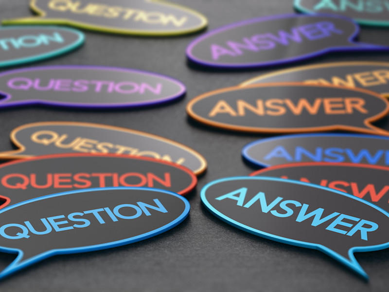 Piles of thought bubble cutouts with the words "question" and "answer" written in colorful letters sitting on a black surface.