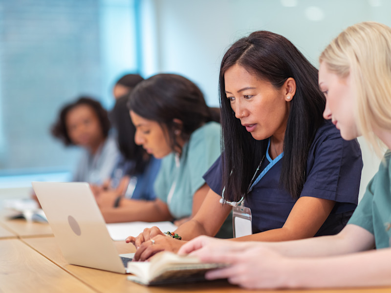 Asian-American nurse educator helping student on computer