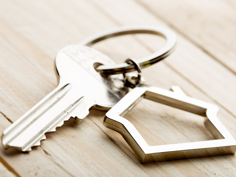 Sterling silver keychain of the outline of a house sitting on a wooden table.