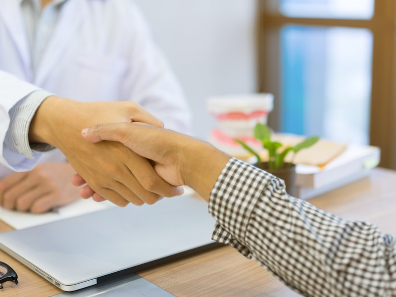 close up dentist hand shake with DSO owner after selling their practice at office desk with