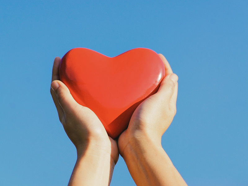 Hand holding a red wooden heart