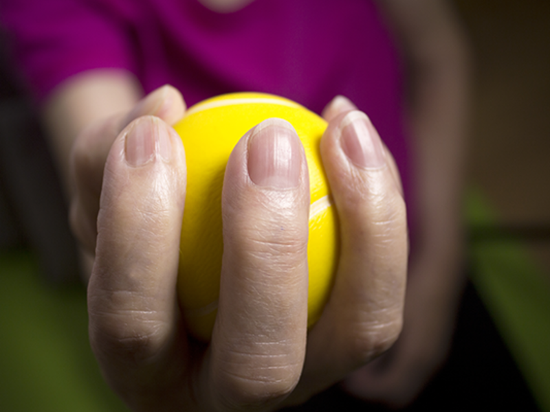 Close-up of woman's hand holding a yellow tennis ball