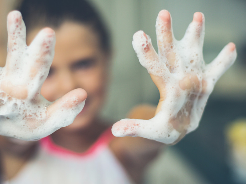Blurry image of woman with soapy hands in foreground.