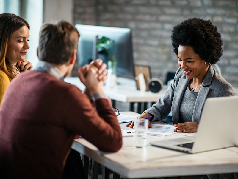 Female real estate agent laughing while going over financials with buyers
