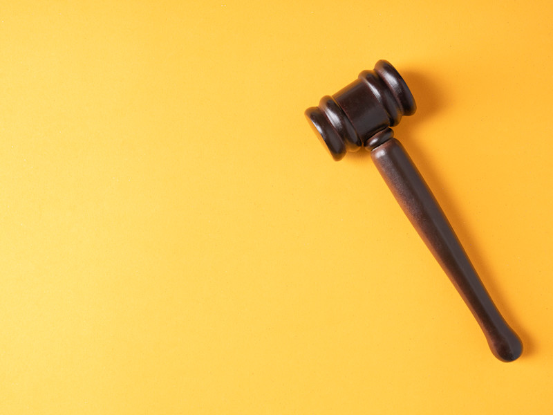 Plain brown gavel against yellow background