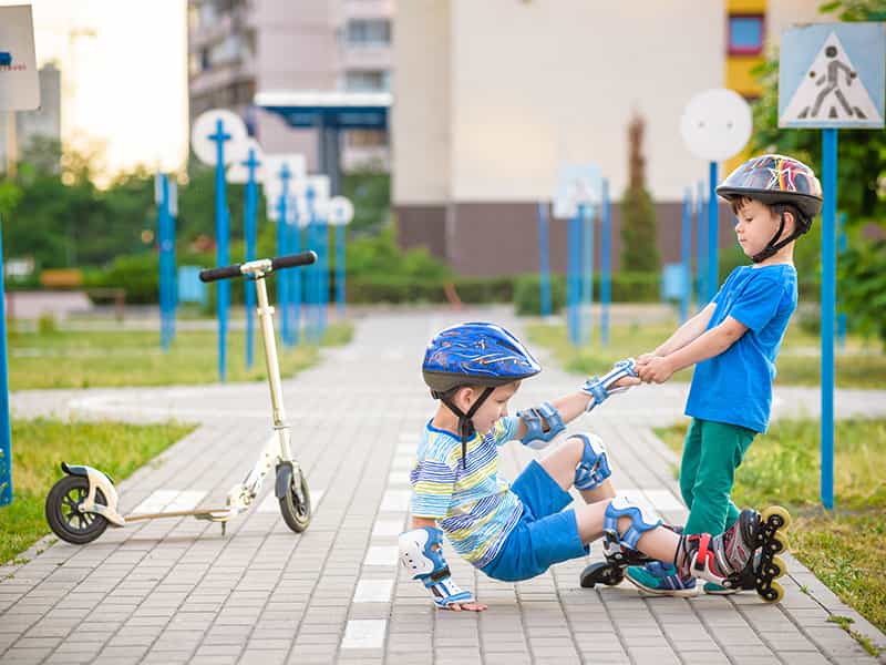Child helping friend stand up on roller skates
