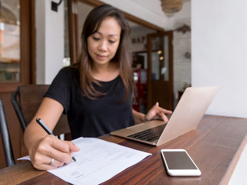 Asian woman writing a resume at a desk