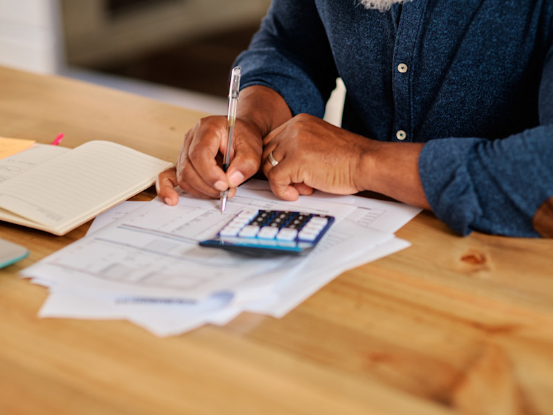 African-American man wearing a blue shirt and calculating commissions for his real estate team.