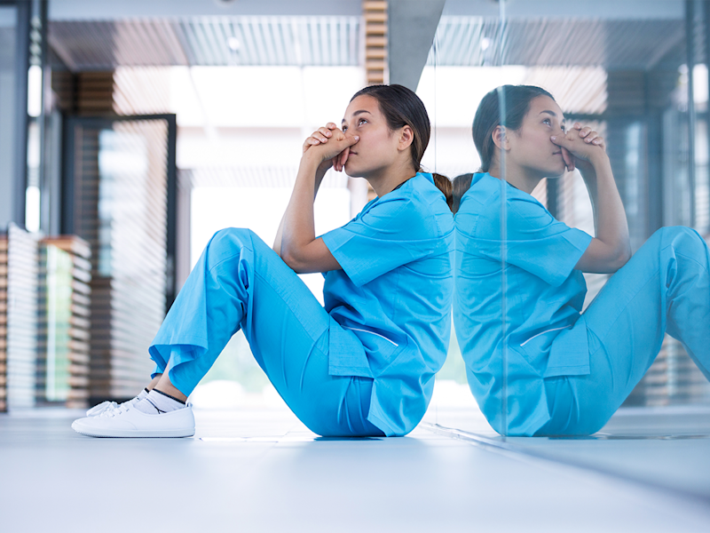 Worried nurse in blue scrubs sitting on the ground