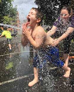 A student runs through a sprinkler during recess