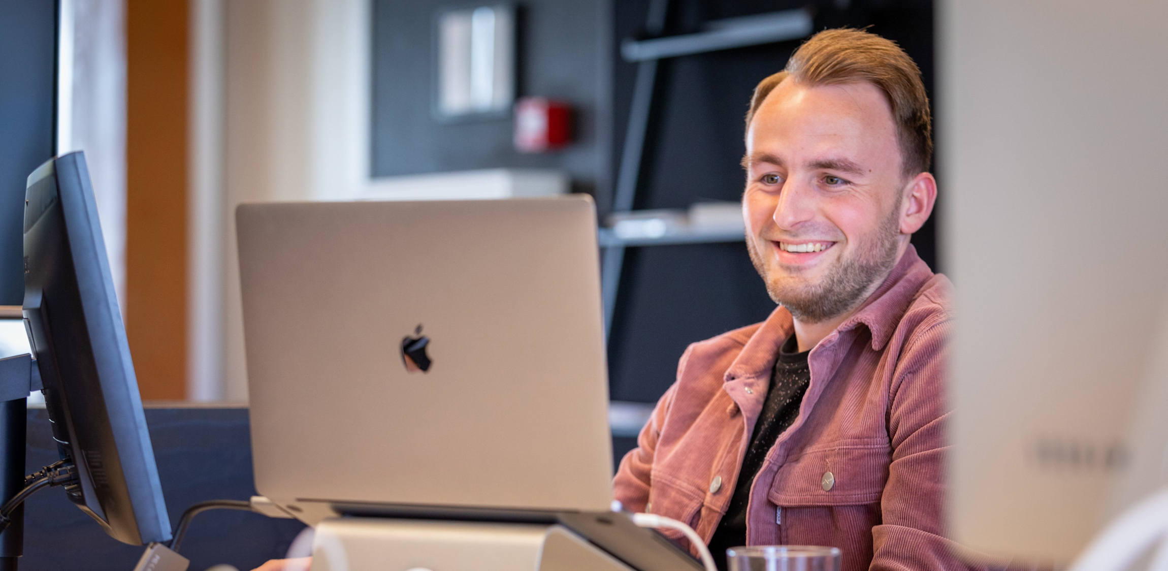 Boy, UI/UX Designer, zit te werken aan een bureau op kantoor