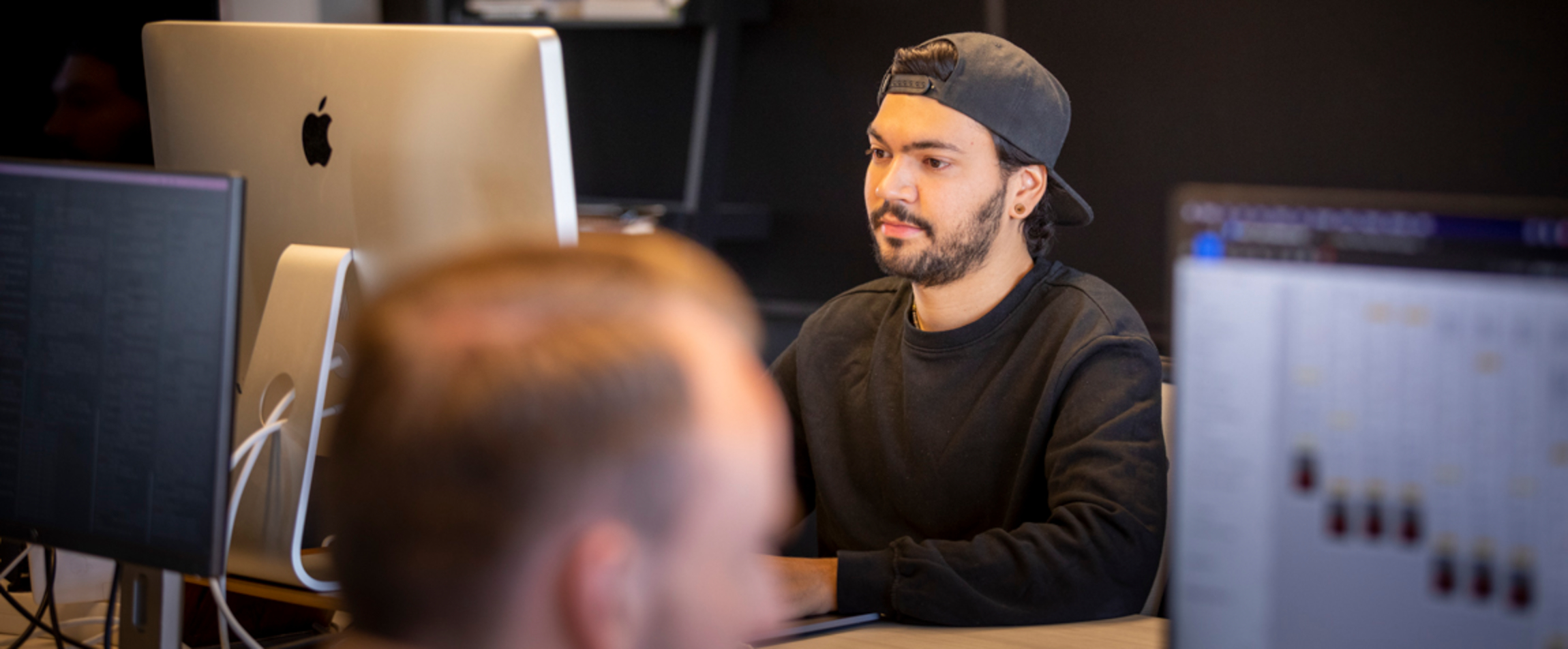 Een developer (Renzel) werkt aan een iMac samen met een designer (Boy).