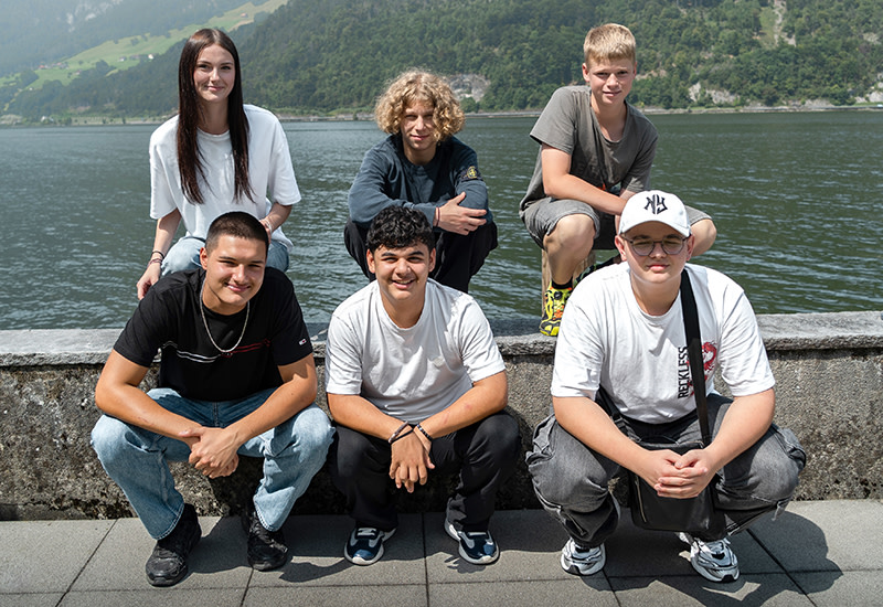 Sechs neue Lehrlinge starten ihre Ausbildung 2025. Das Gruppenfoto am See zeigt die motivierten Jugendlichen bei sonnigem Wetter und mit viel Vorfreude auf ihre berufliche Zukunft.