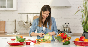 Mujer cortando vegetales en su cocina