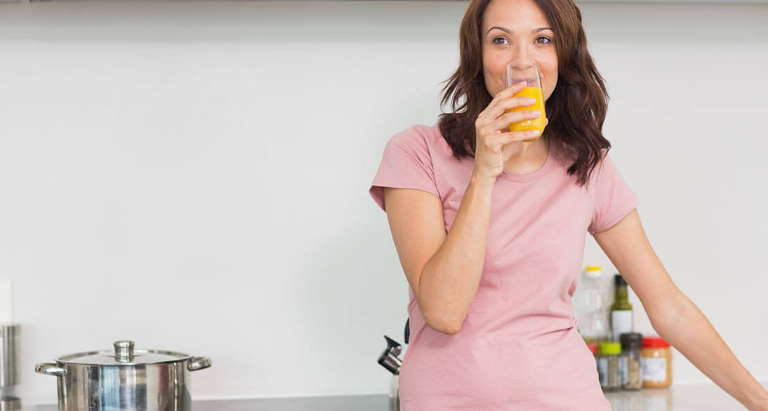 Mujer tomando vaso de jugo de naranja