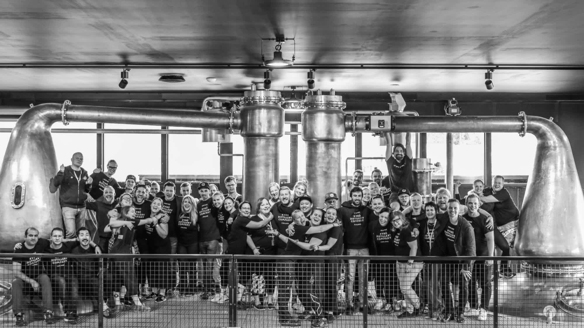 A black and white image of the Kyrö people: most of the Kyrö team pictured in front of the whisky pot distills in Isokyrö, Finland. 