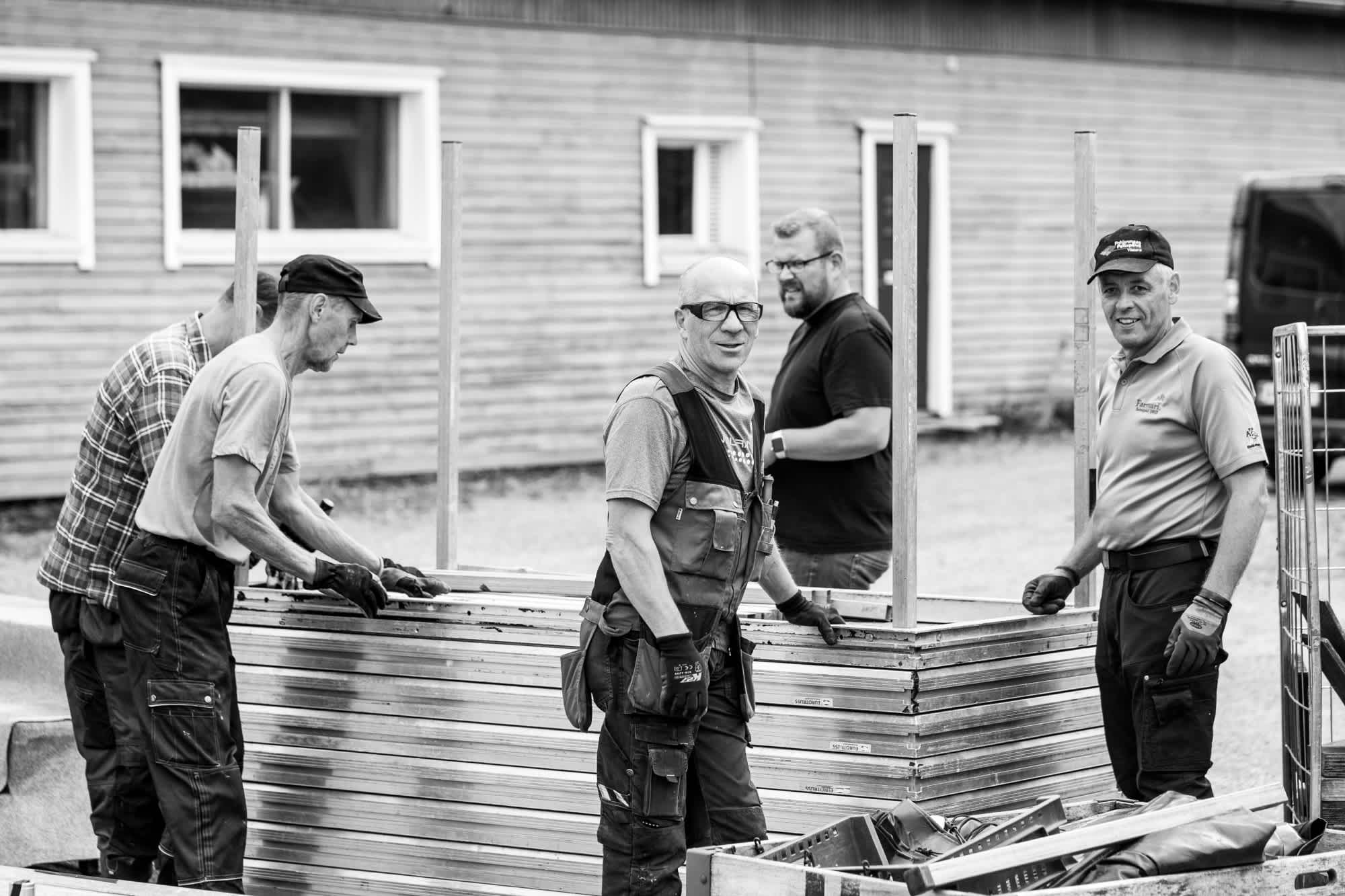 Black and white image of a group of construction workers building something. 