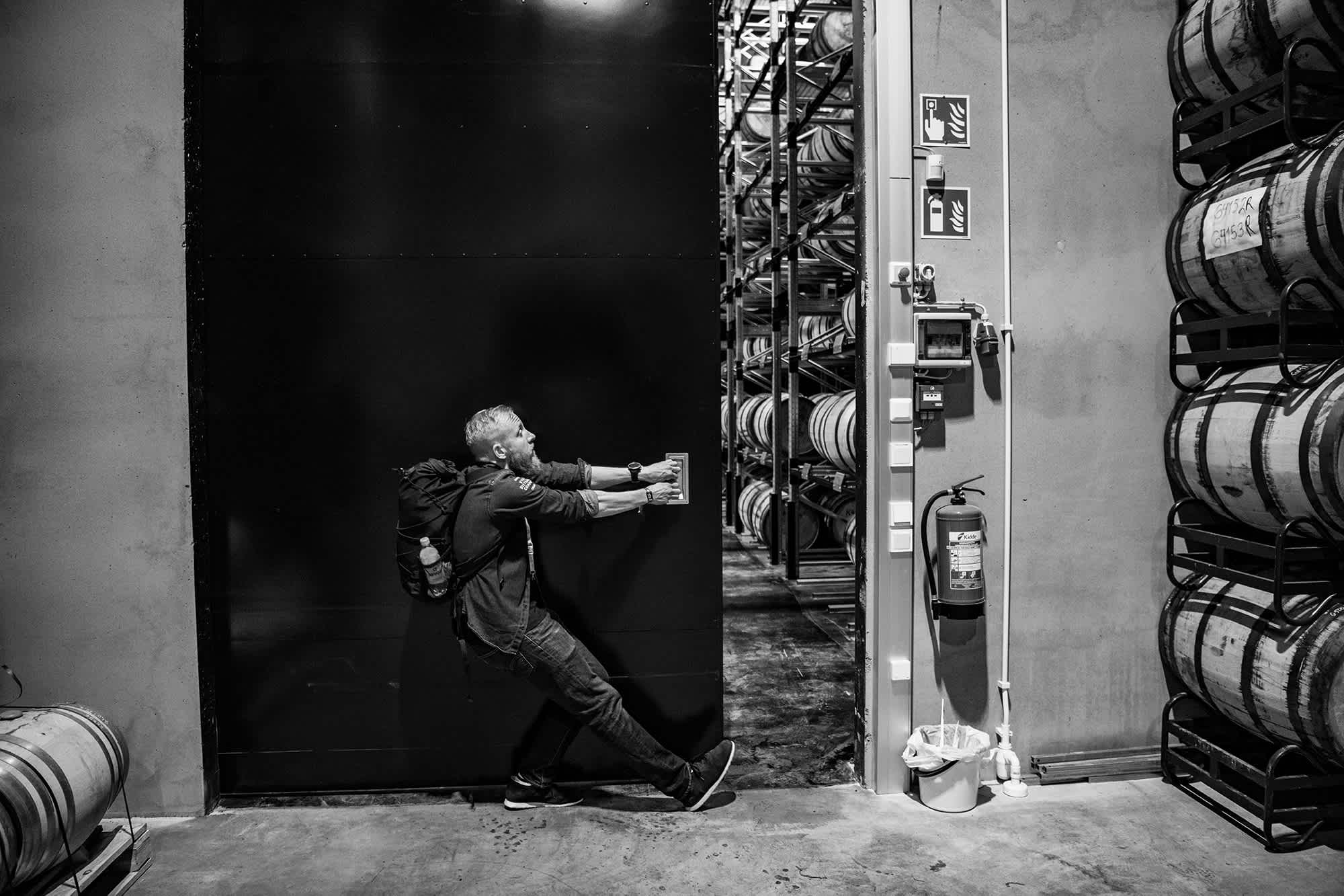Black and white image of co-founder Mikko Koskinen opening a door in the whisky barrel warehouse. 