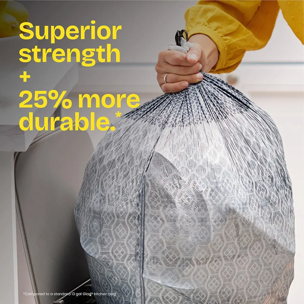 A person pulling a gray-color trash bag out of a trash can. The words "Superior strength + 25% more durable." in yellow