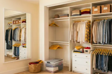Organized closet with neatly hung clothes, folded sweaters, labeled bins and drawers